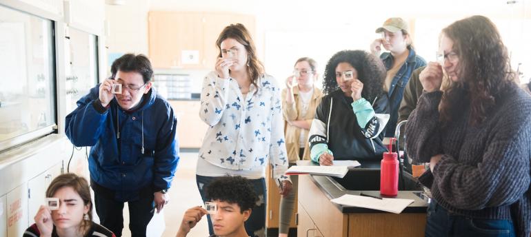 Students in a classroom looking through a microscope