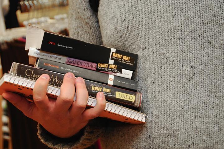 Student holds rented books and a notebook