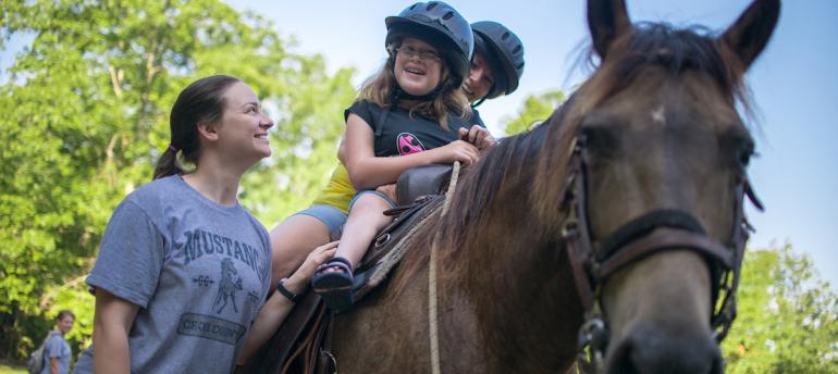 Camp Horizon Child on a horse with a woman holding the rope