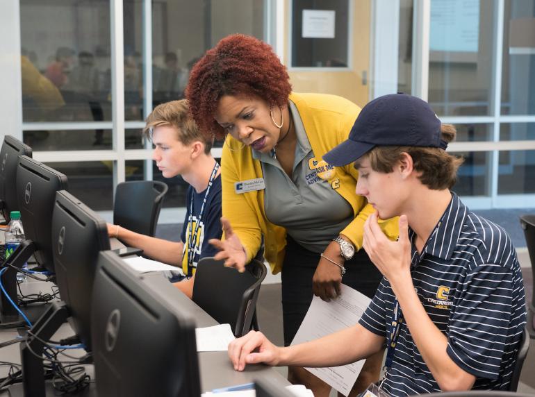 Teacher helping student as computers