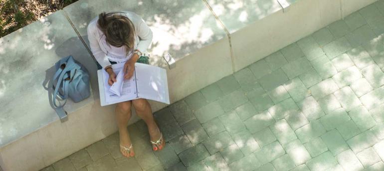 Student Sitting on ledge doing homework