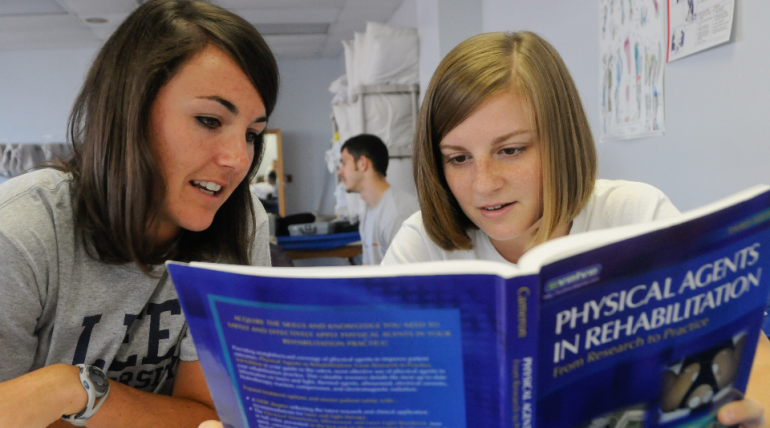 Two students read a textbook