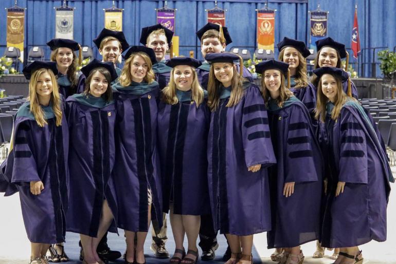 Group of students pose in graduation gowns