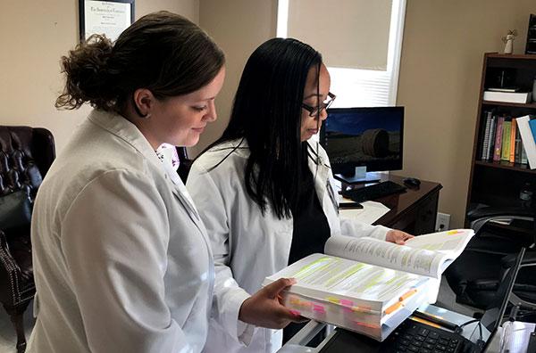 Two nursing students read textbook