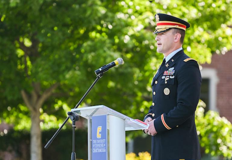 Man in military uniform stands at podium outside UTC