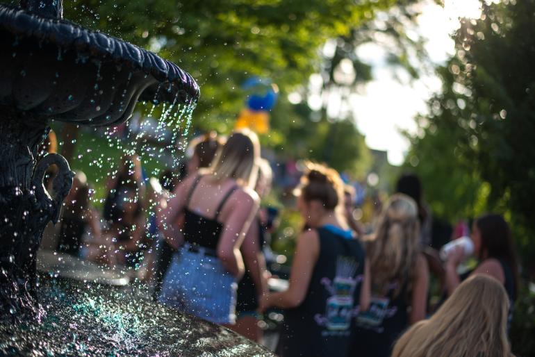 Artistic photo of water drops from a fountain, with students in a blurred background, shot on a Dutch Angle 