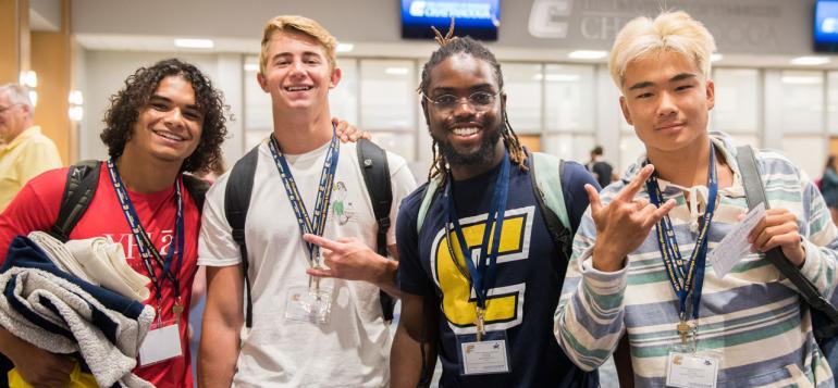 Male Freshmen Orientation participants smiling and displaying the Power C hand sign