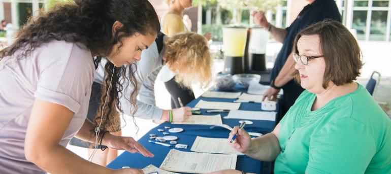 student standing over table registering to vote