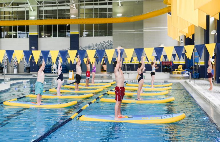 Paddleboard Yoga This picture shows individuals participating in paddleboard yoga in the UTC Aquatic and Recreation Center.