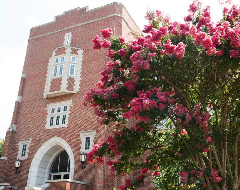 Flowers bloom beside the main entry of Fletcher Hall, home of the Gary W. Rollins College of Business