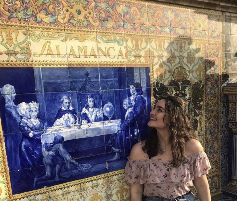 Student posing in front of tile art in Spain