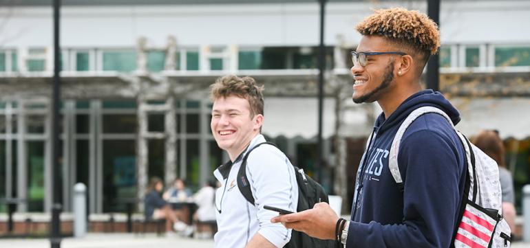 Two students walking in front of library smiling
