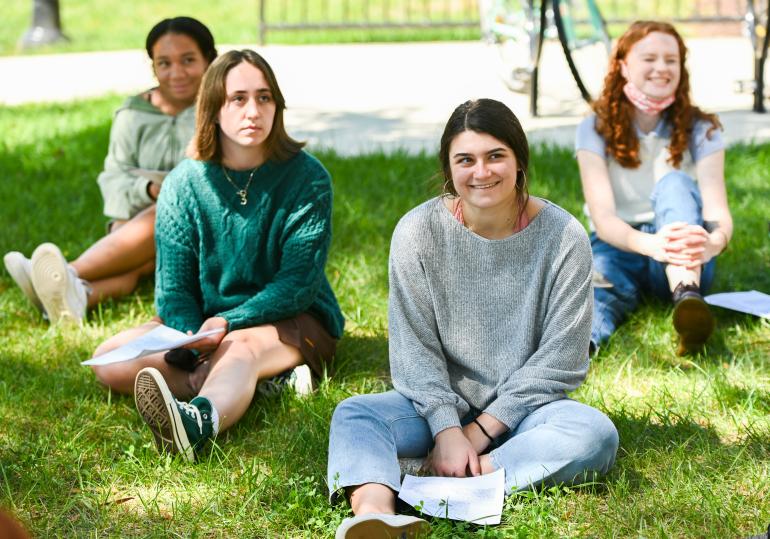 Humanities students outside in grass listening to teacher