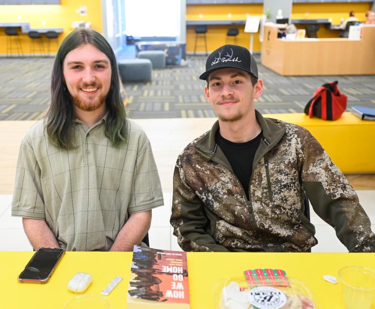 Two men smiling at camera while sitting