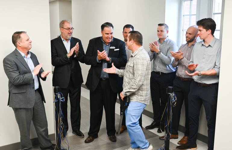 Eight people shaking hands after a ribbon cutting ceremony.