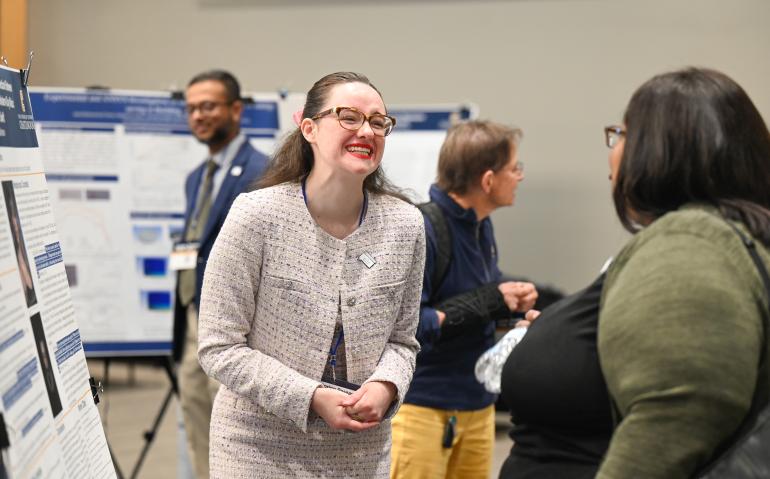 Student in pink suit presenting at 2023 Spring Research Conference