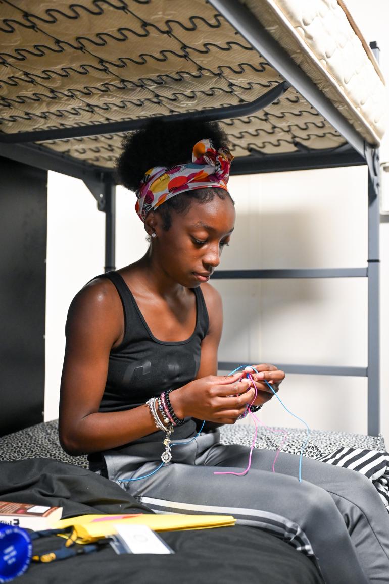 A student braiding a keychain at summer camp