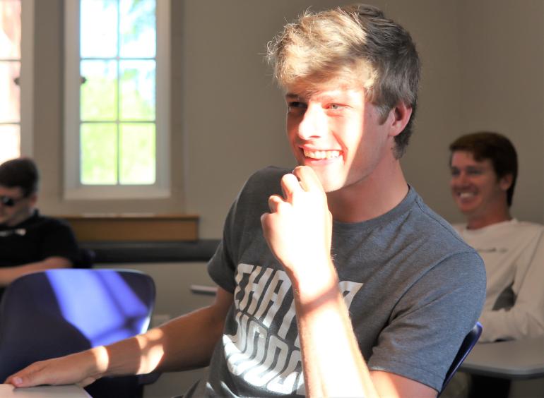 College student in gray t-shirt laughs during a sales class at the UTC Gary W. Rollins College of Business.