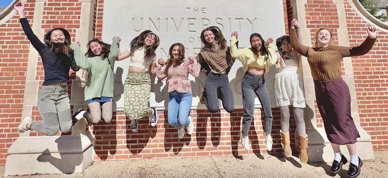 Members of Delta Phi Lambda jump together in front of UTC sign 