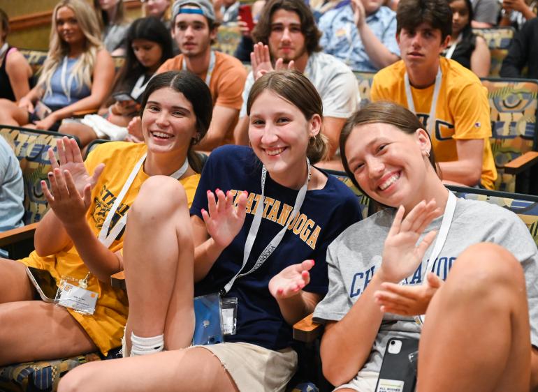 Three female students in a crowd at student orientation