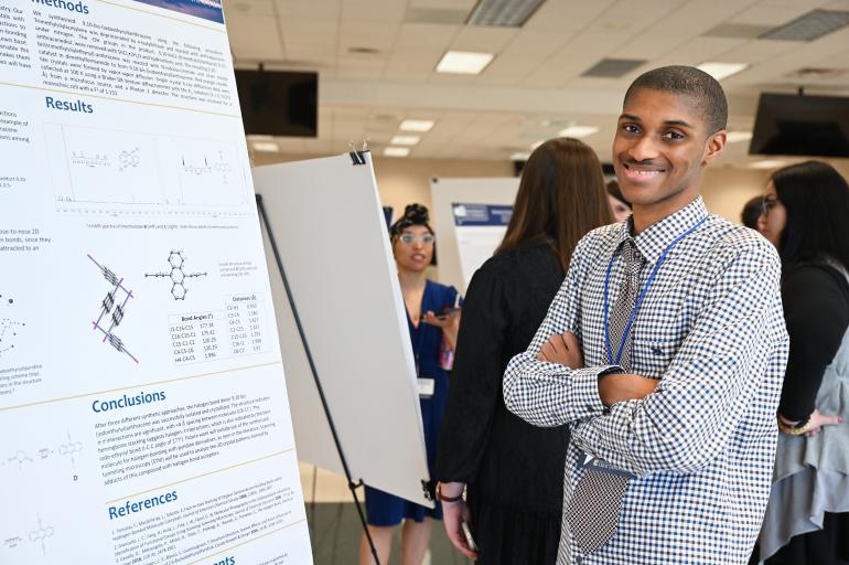 Male student standing in front of a chart at the UTC research fair