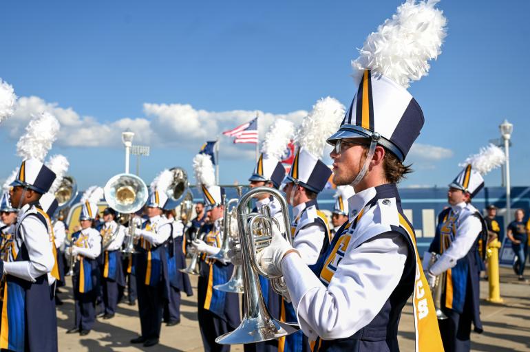 A horn line in the UTC Marching Mocs in uniform on the field