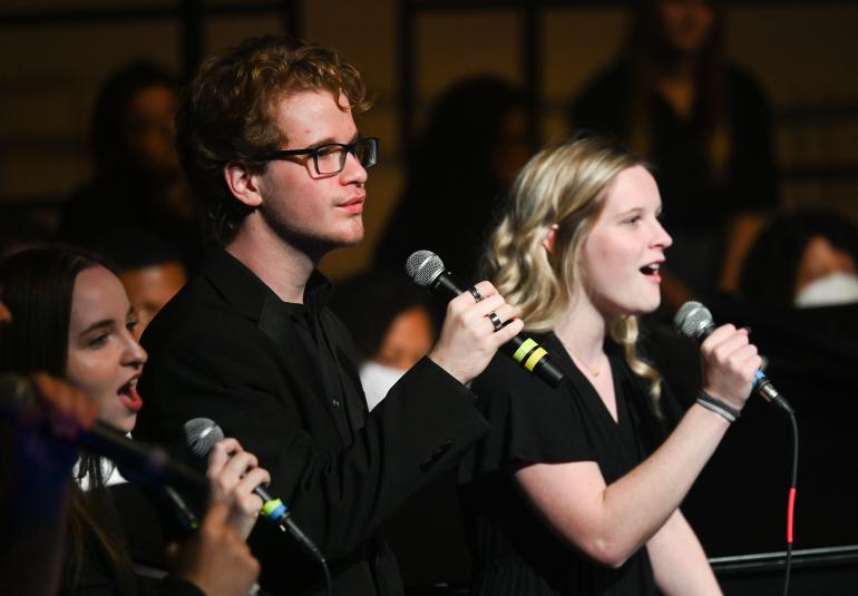 Close up of members of the UTC SInging Mocs holding microphones