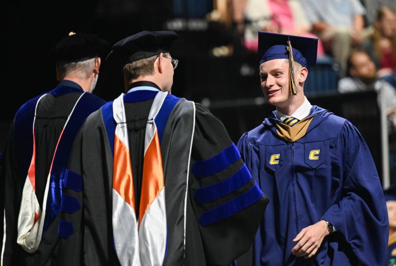 Grad student shaking hands as he walks across the stage