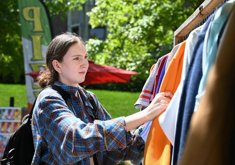 Student looking through a rack of clothes at mocs marketplace