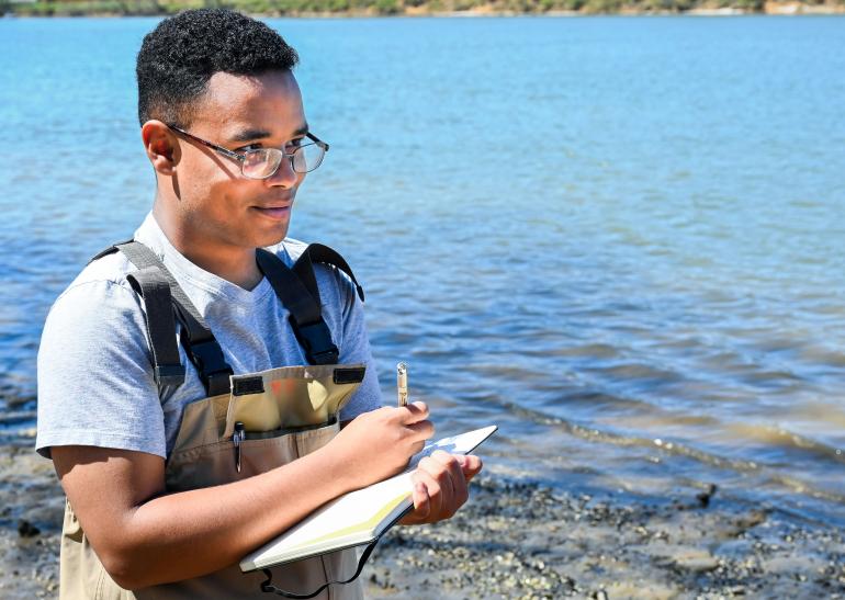 Field work for electrofishing Picture of student taking field notes by the Tennessee River.