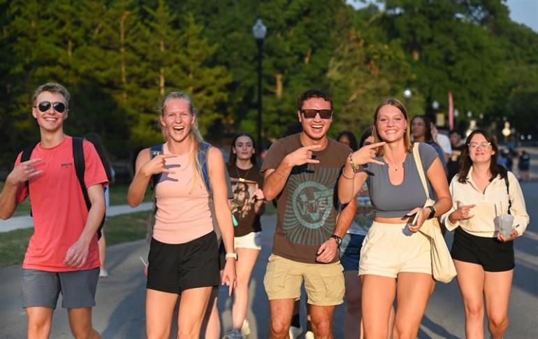 utc students at sunset holding up the power c hand gesture