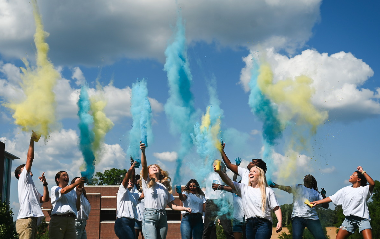 Students throwing blue and yellow powder into the air