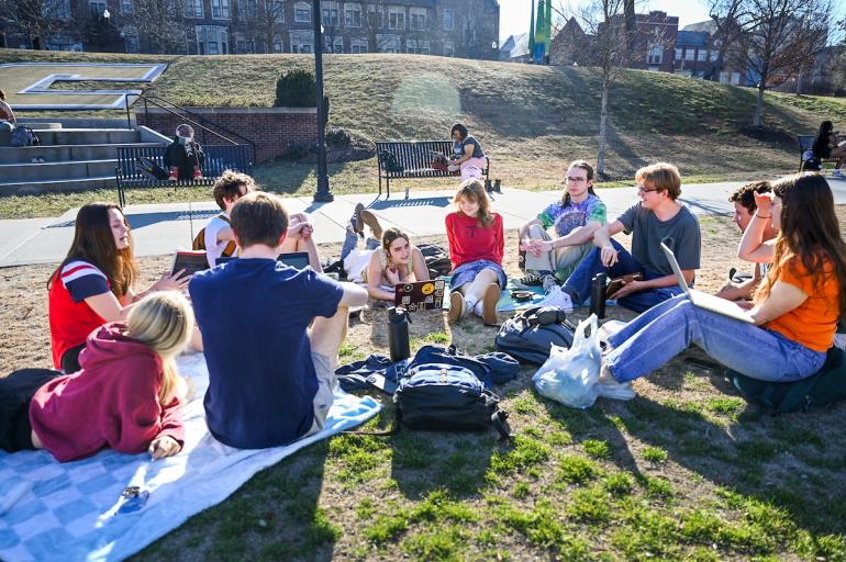 a group of students sitting in a circle outside