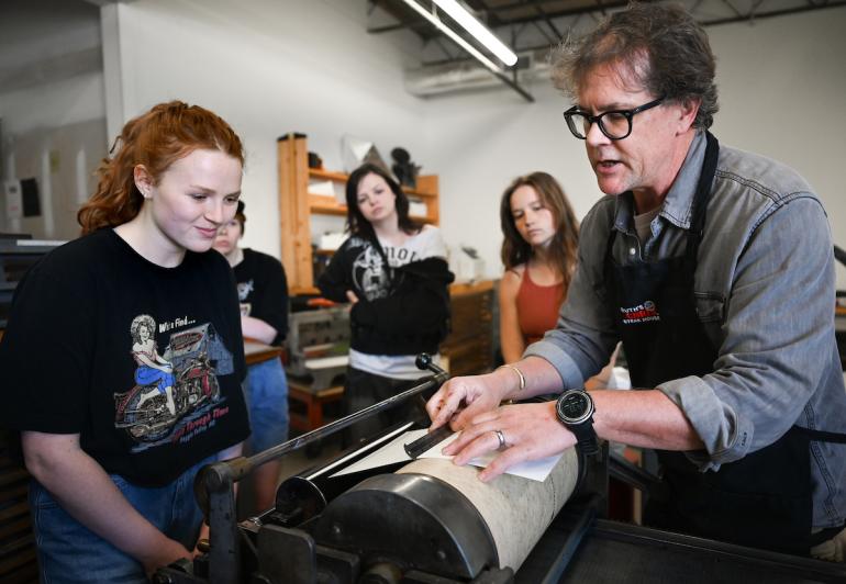 Professor Matt Greenwell instructs students on using a Vandercook press for letterpress.