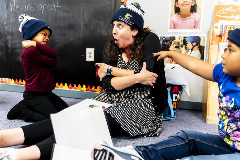 An ABC Teaching Artist engages students, all wearing UTC gear