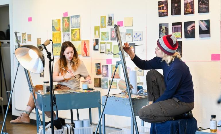 Two students work at easels in a Figure Drawing class.