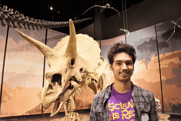Student observing a dinosaur skeleton in a museum setting