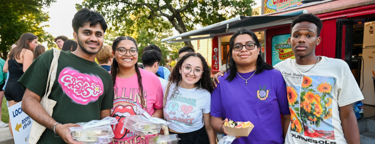 Five students holding food from food trucks at a campus event. 
