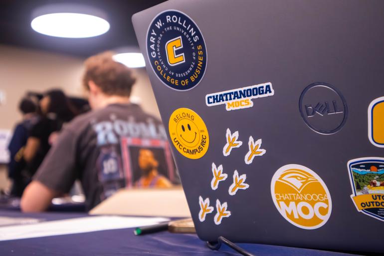 A student laptop with various UTC stickers on the back.