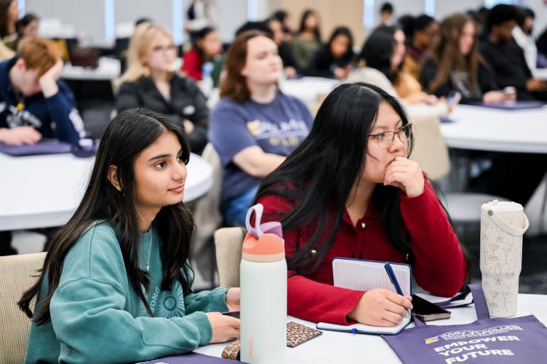 Two students listening and taking notes while at Empower event