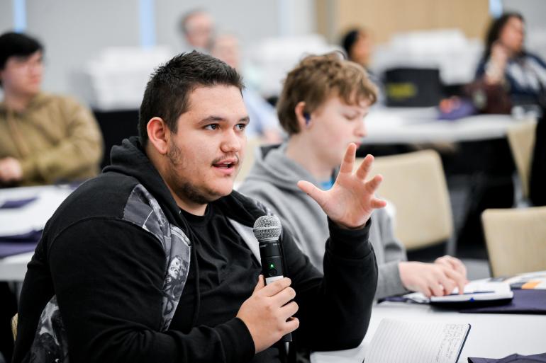 A student holds a microphone and asks a question to the panelists during the Empower event.