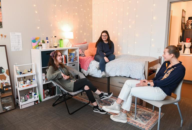 Three students in a bedroom chatting
