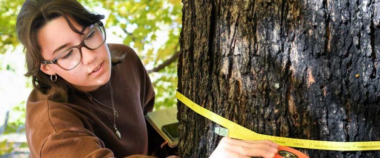 UTC female student measuring a tree with a ruler tape