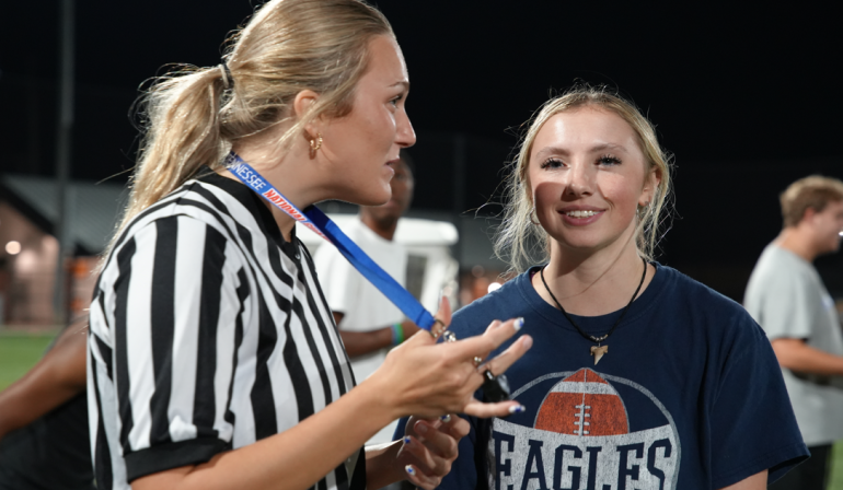 A flag football official talking to a flag football player. 