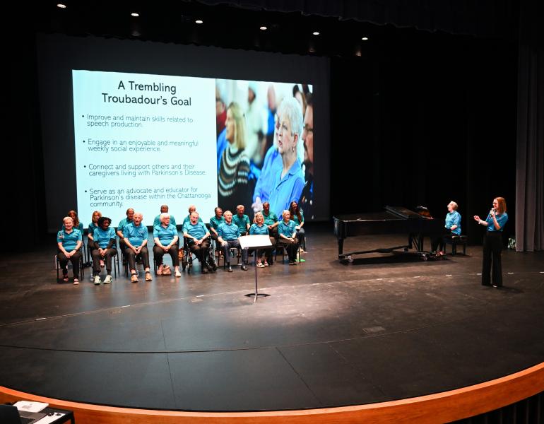 Singers on stage with a lecturer smiling