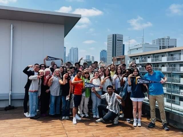 Students holding Chattanooga pennants on rooftop in Japan
