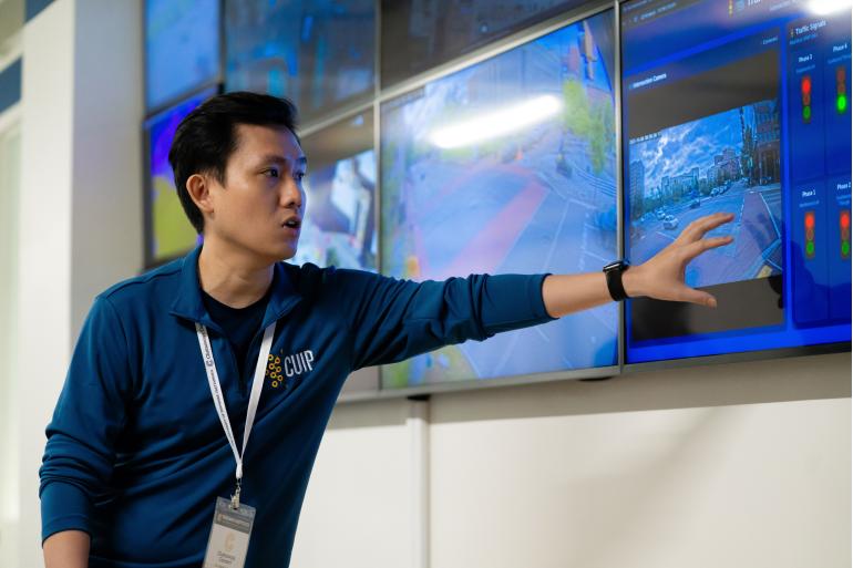 Student pointing to information on a screen as he explains the Traffic Management Center.
