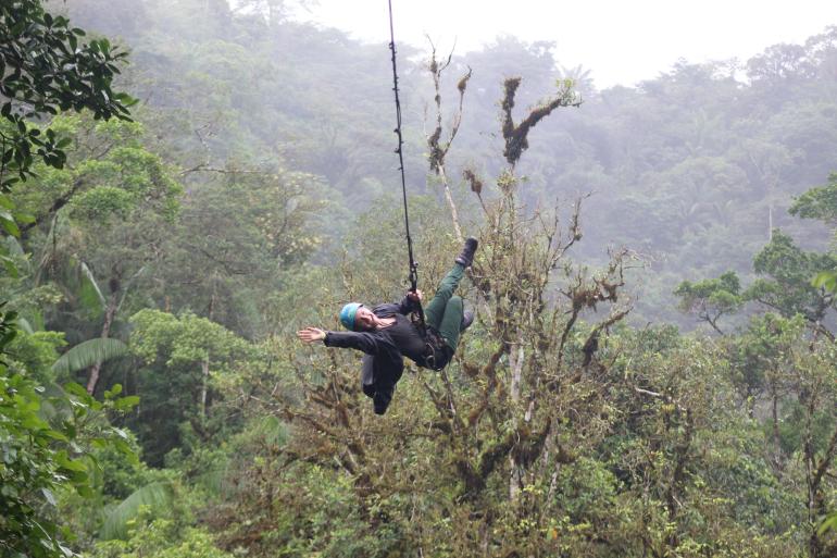 Person zip-lining through Costa Rica rainforest canopy
