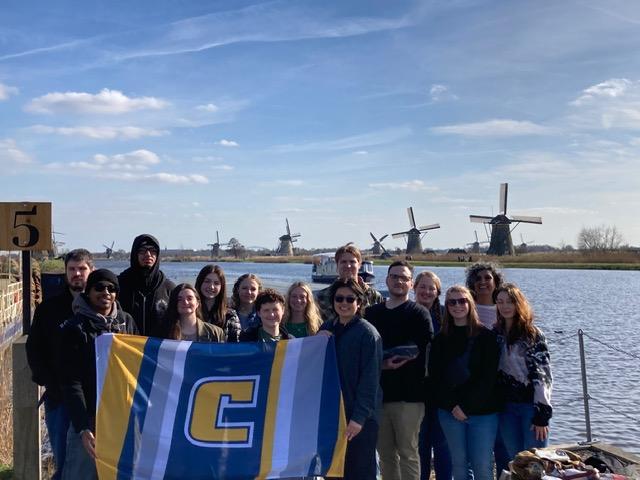 UTC students with flag in front of Dutch windmills