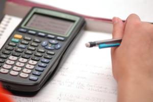 hand with pencil next to calculator